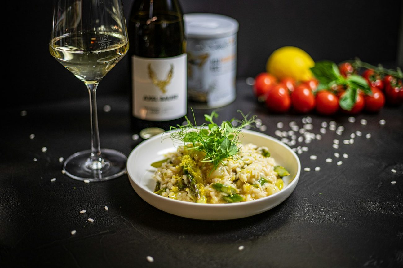 Mesa posta com risoto, taça de vinho branco e tomates frescos